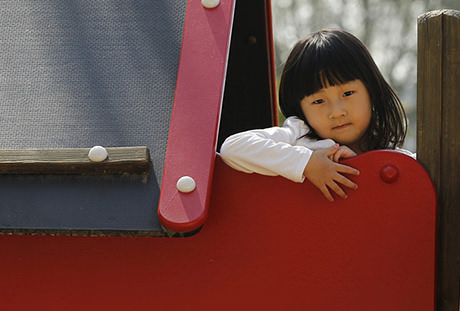 A young Asian girl on a slide.